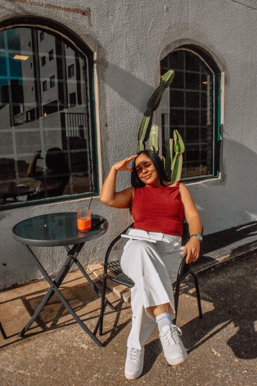 Gisele Lopes, estrategista comercial, sentada ao sol com a mão na testa