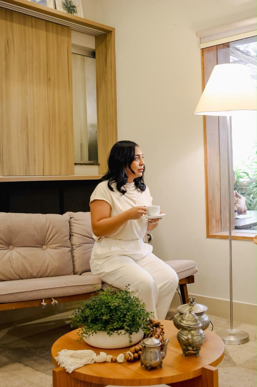 Gisele Lopes, estrategista comercial, sentada no sofá com uma xícara de café